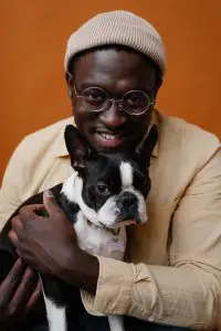 black person holding black and white puppy in his lap